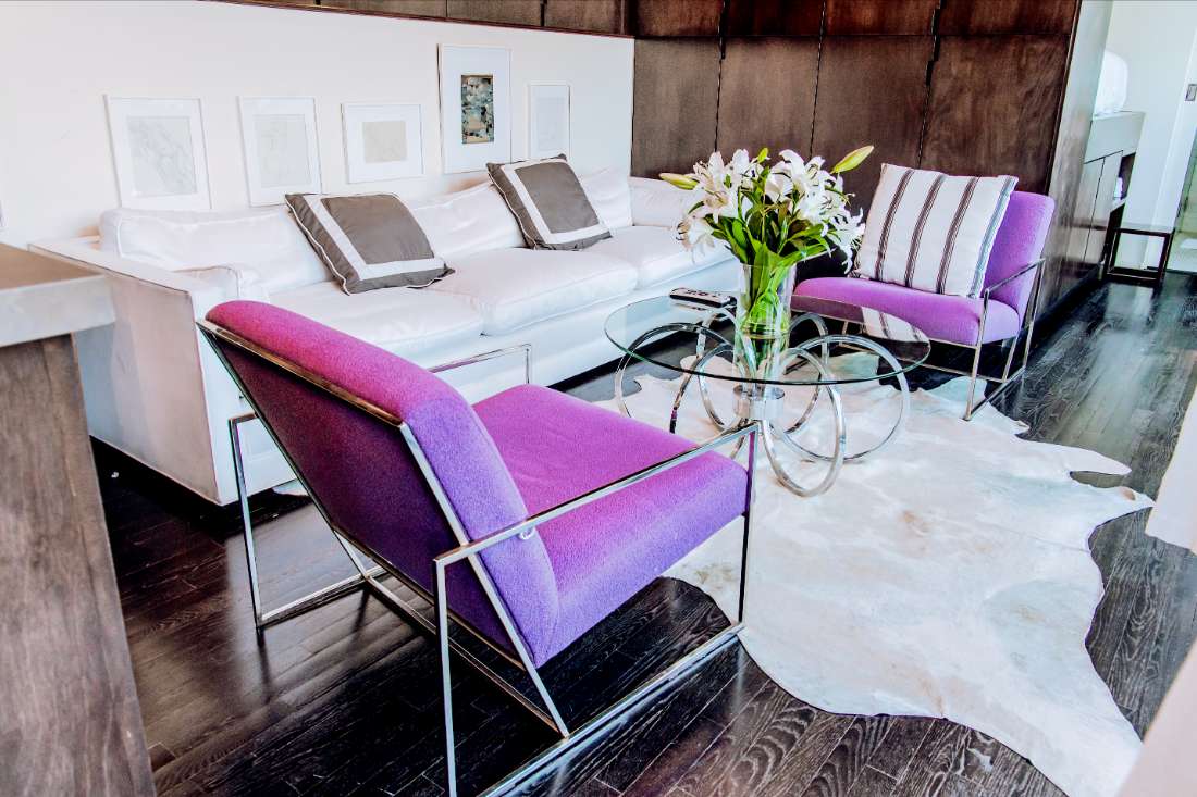 A living room with purple chairs and white walls