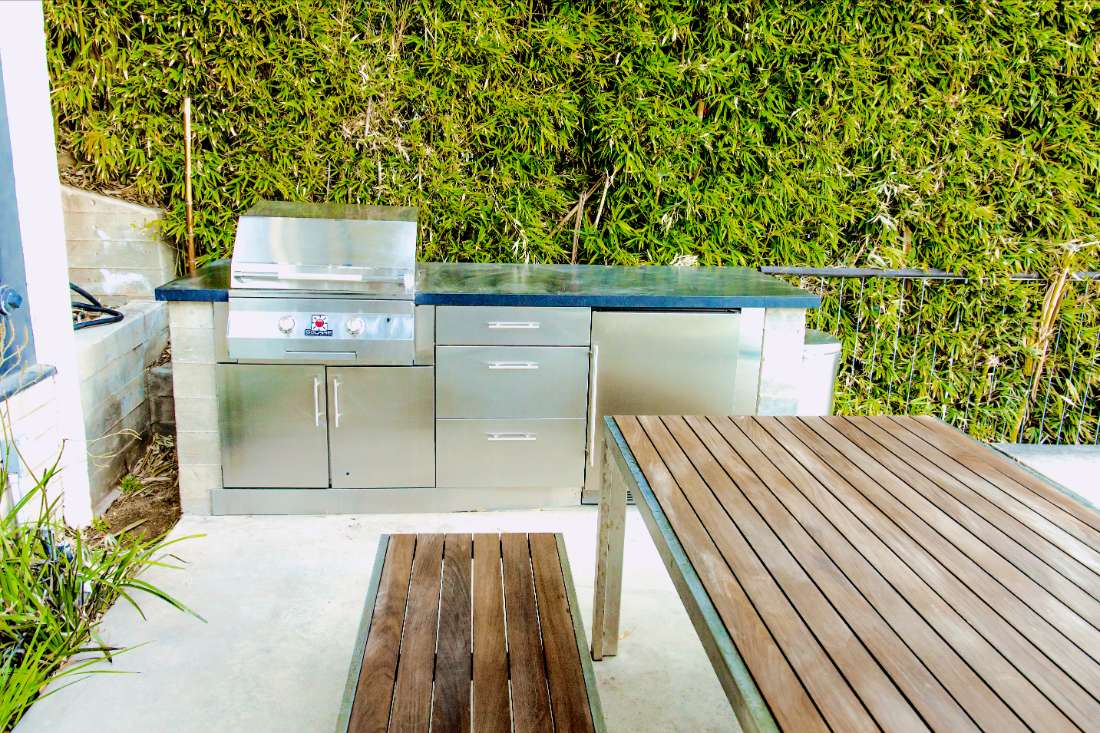 A stainless steel outdoor kitchen with an outside table.