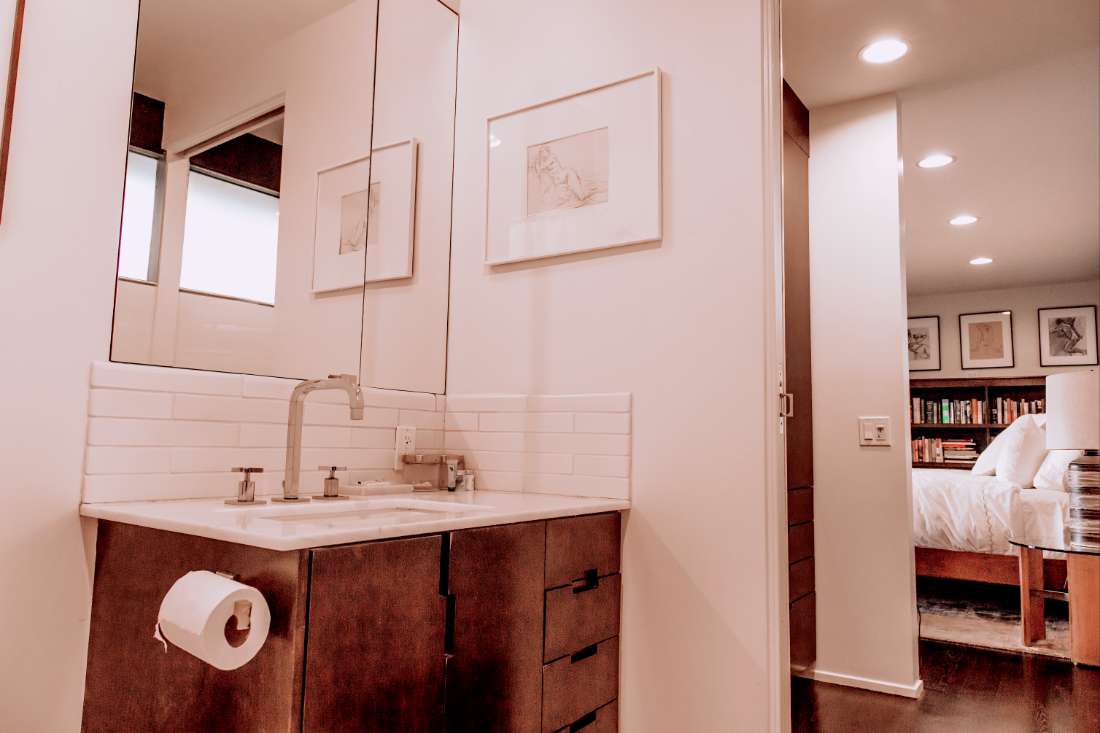 A bathroom with white walls and wooden cabinets.