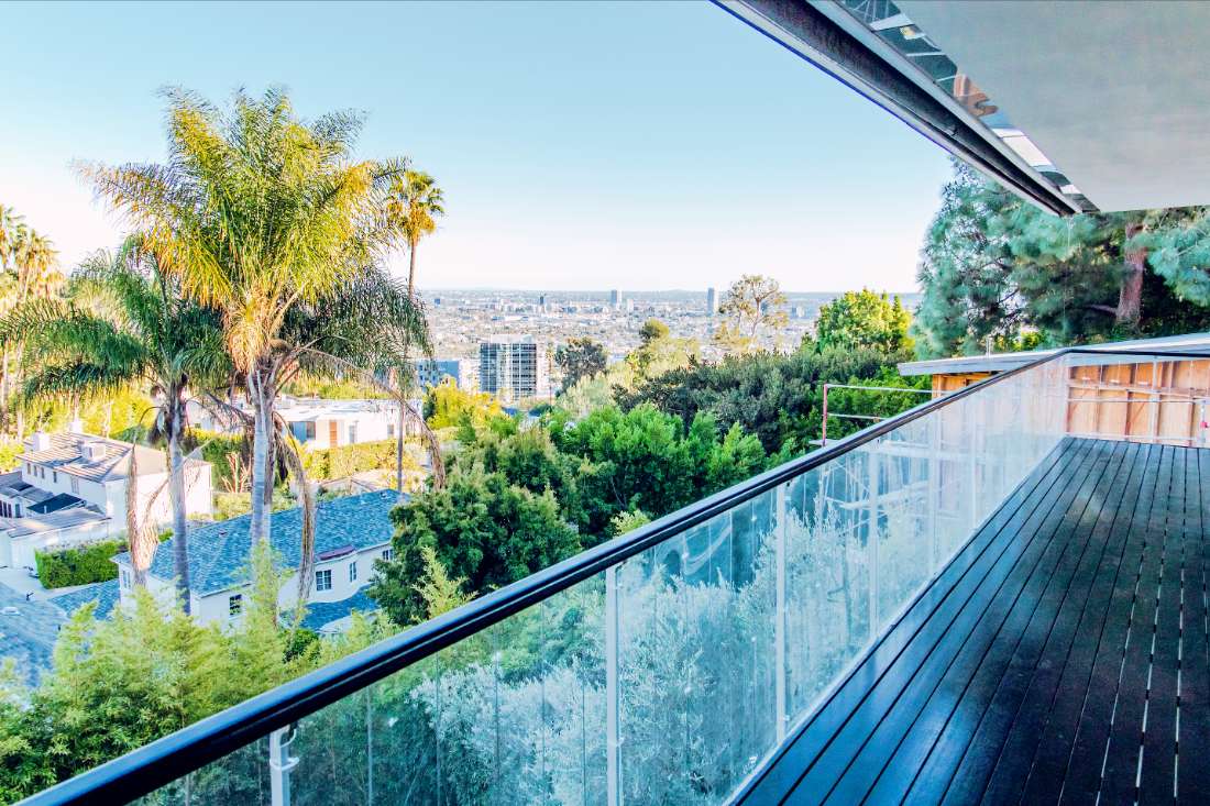 A balcony with glass railing and palm trees