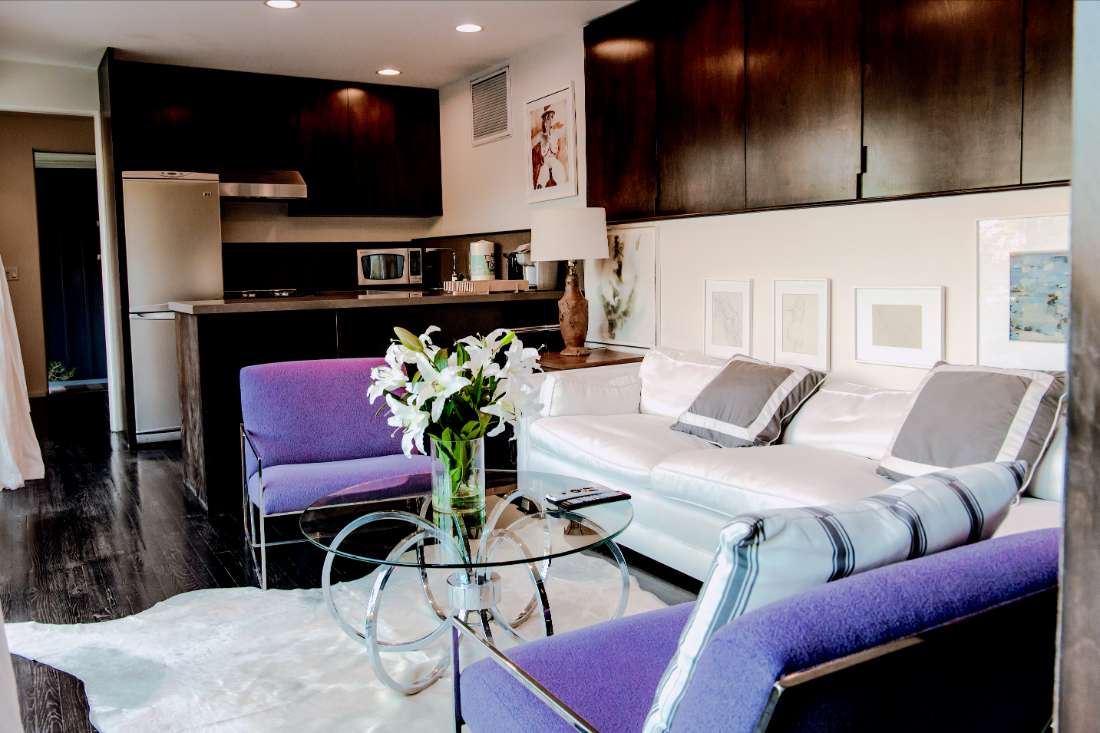 A living room with purple chairs and white furniture.