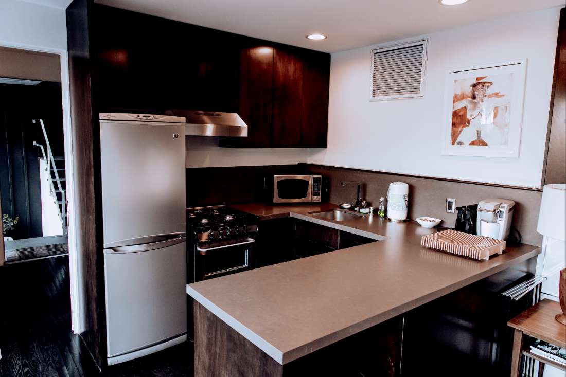 A kitchen with a refrigerator, microwave and oven.