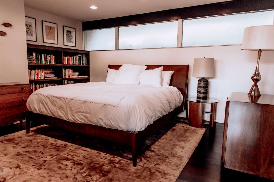 A bedroom with a bed, nightstand and bookshelf.