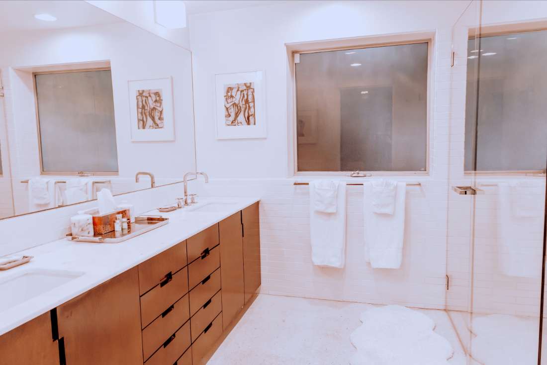 A bathroom with white walls and wooden cabinets.