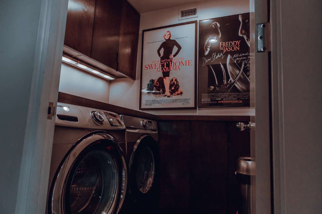 A washer and dryer in a room with posters on the wall.