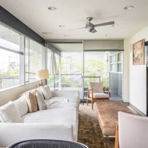 A living room with white furniture and large windows.