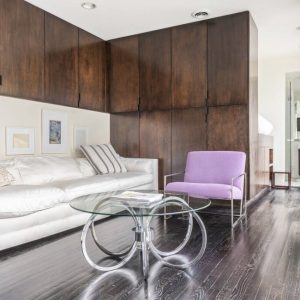 A living room with wood paneled walls and white furniture.