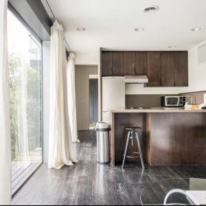 A kitchen with wooden cabinets and floors, and a sliding glass door.