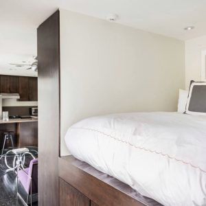 A bed room with a white bedspread and pillows