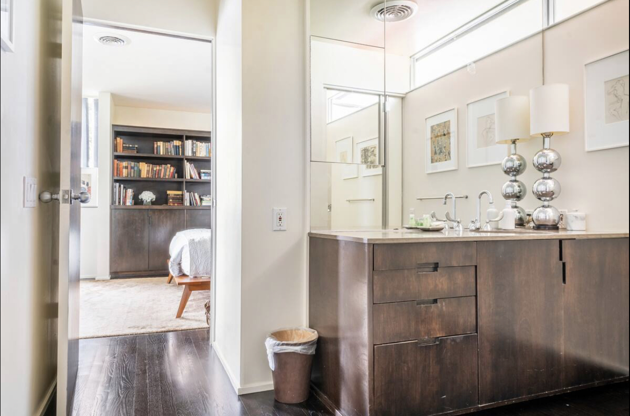 A bathroom with a large mirror and wooden cabinets.
