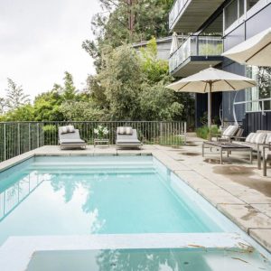 A pool with chairs and umbrellas in the background.