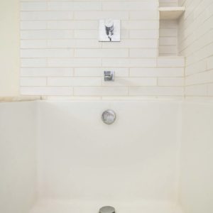 A white tiled bathroom with a shower and tub.