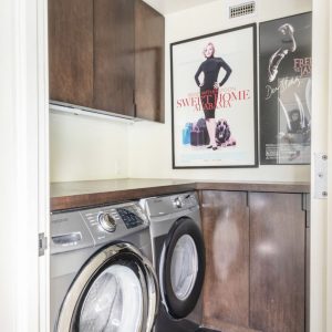 A laundry room with two machines and a poster