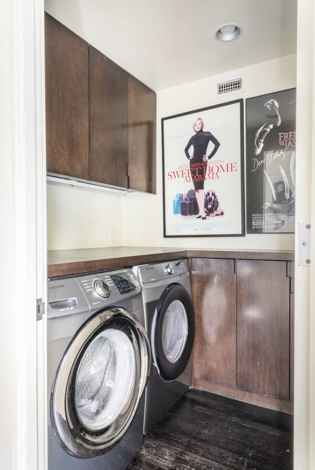 A laundry room with two machines and a poster