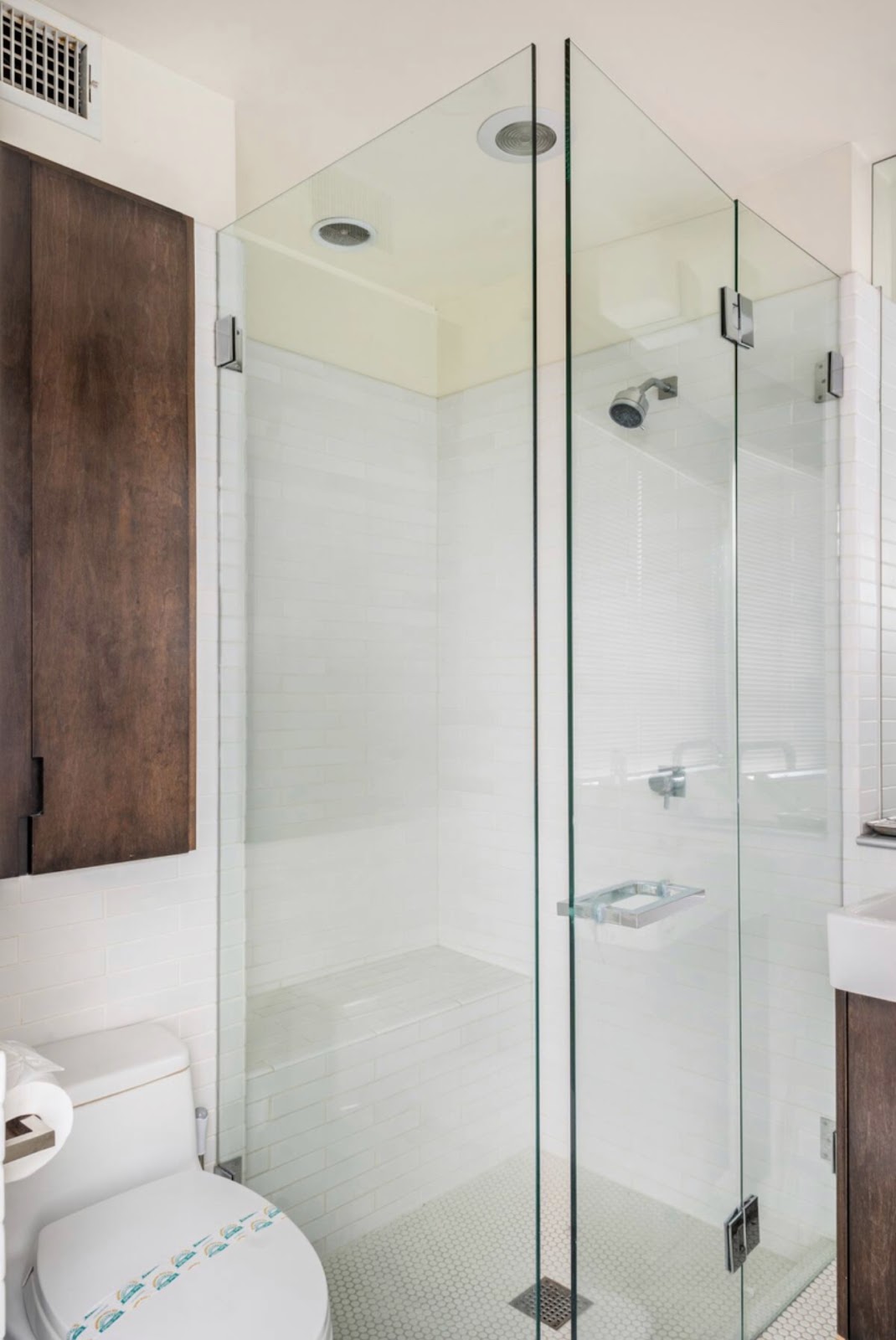 A bathroom with a glass shower door and white walls.